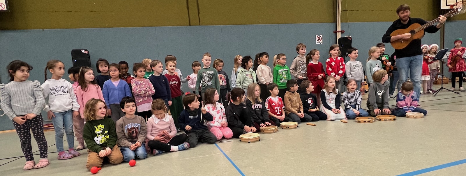 Klassen 1a und 1b singen ein Weihnachtslied unter der Leitung von Herrn Meyer von der Kunst- und Musikschule